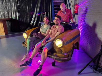 Een voorkant van een auto met een bank ingebouwd als dj meubel, met mensen erop zittend